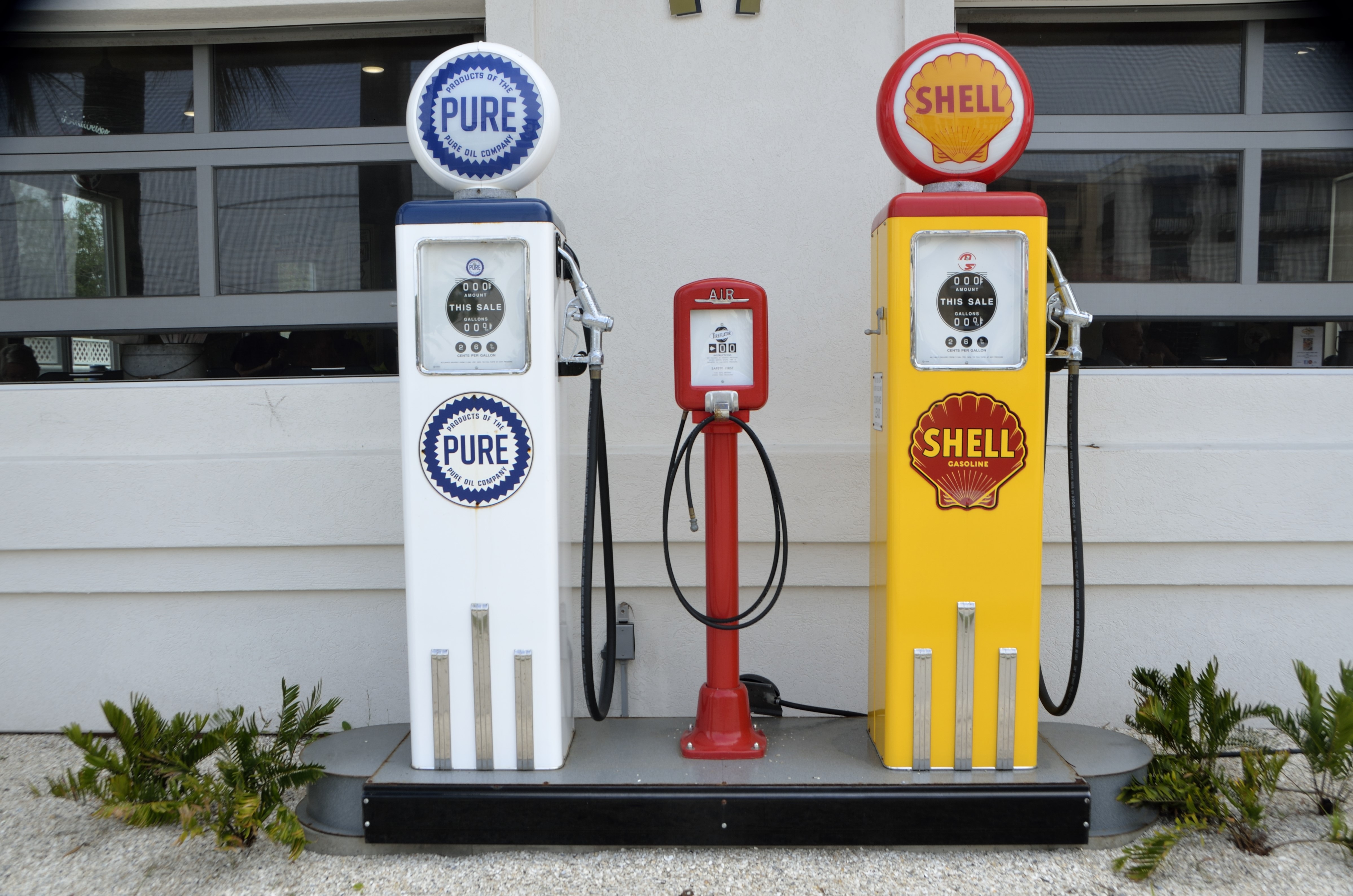 A public domain image that pictures two vintage gasoline pumps and one vintage air pump in between them.